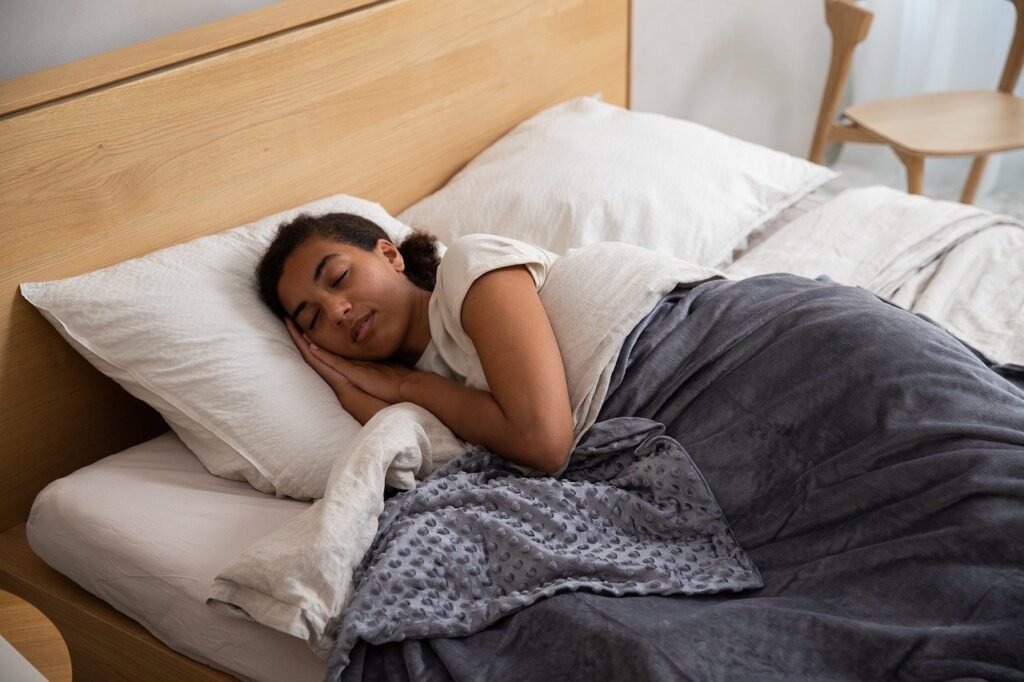 A woman peacefully sleeping in bed with elevated head, covered with a cozy gray blanket and resting her head on a soft pillow in a calm and comfortable bedroom environment