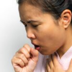 Woman covering her mouth while coughing