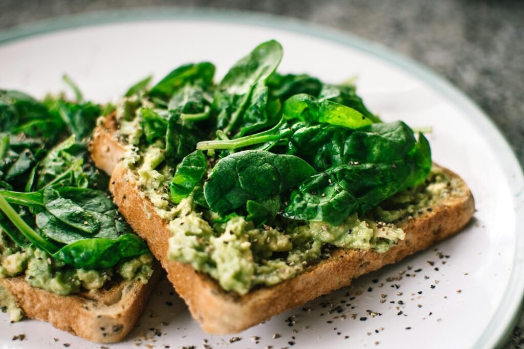 Spinach Leaves and Avocado on Sliced Bread on White Ceramic Plate