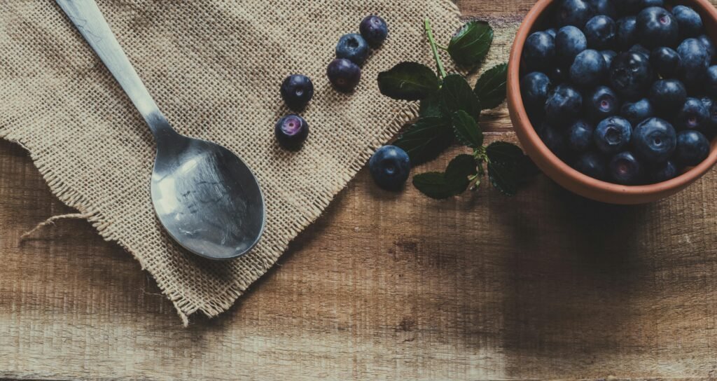 Blueberries on Mug and Brown Surface Near Spoon as a superfood