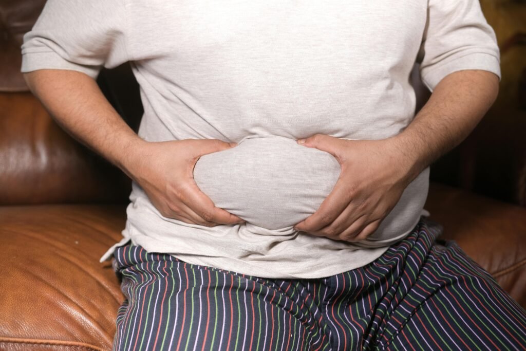 A Man Holding His Tummy. Ways to reduce belly fat